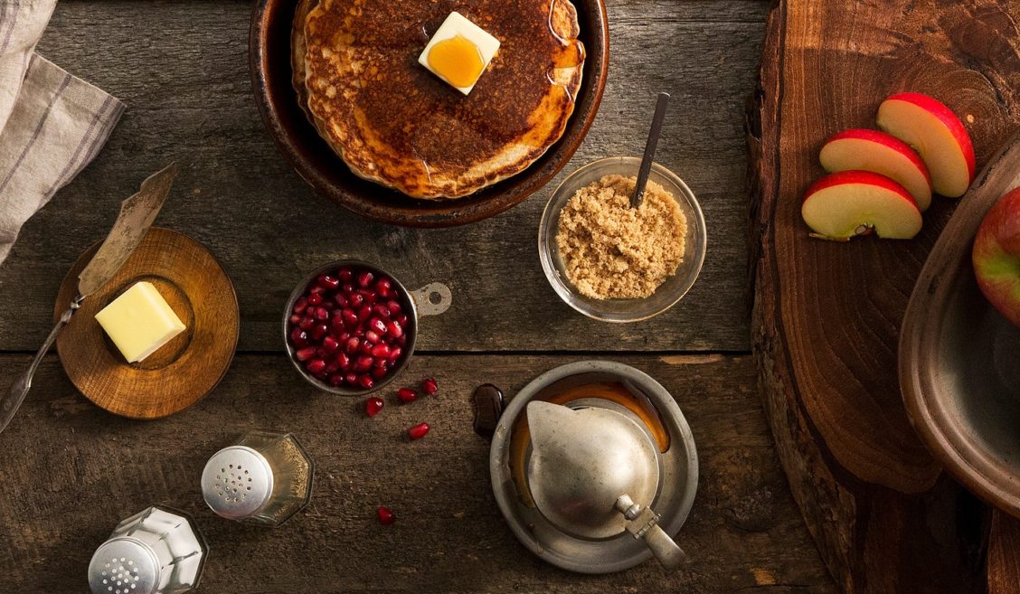 Overhead photography of a spread of pancakes and toppings on a wooden table
