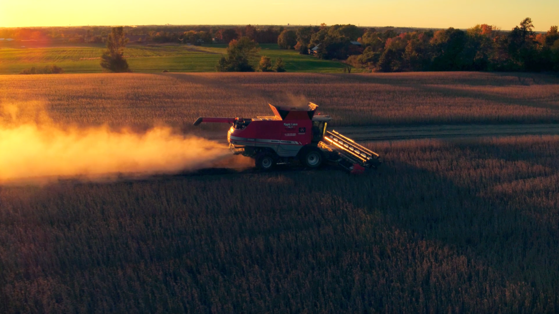 Drone photo of a harvester in a farm field at sunset