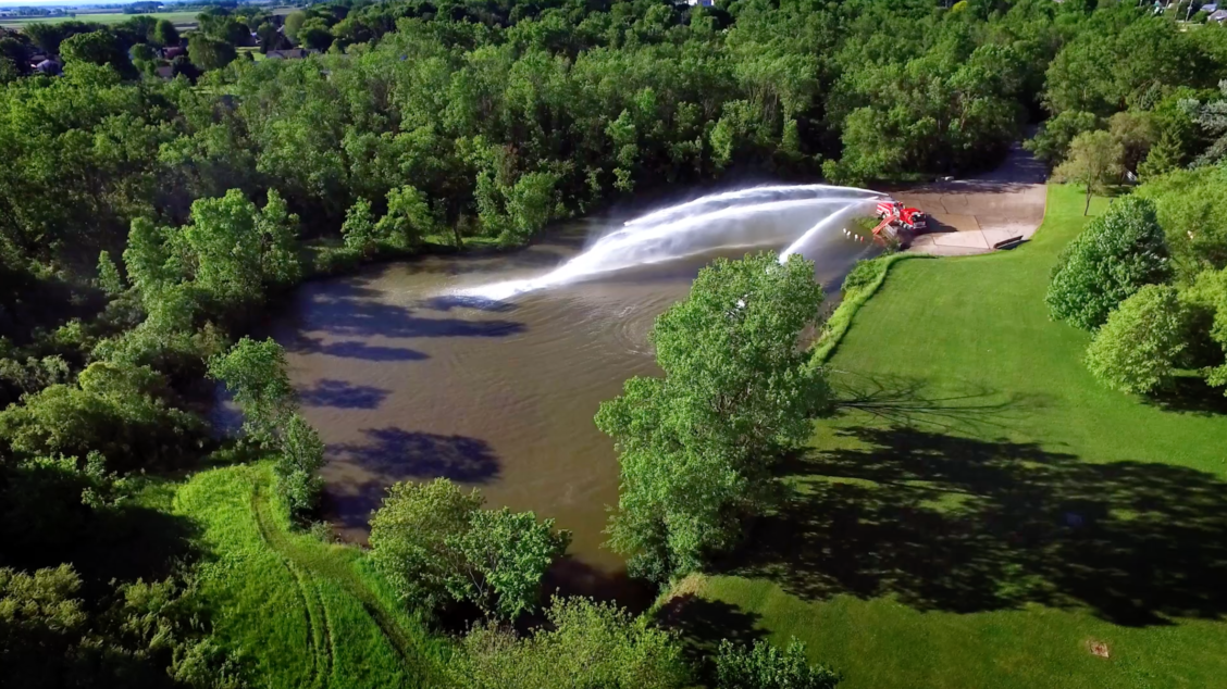 Aerial capture of a fire truck emptying it's hose into a body of water