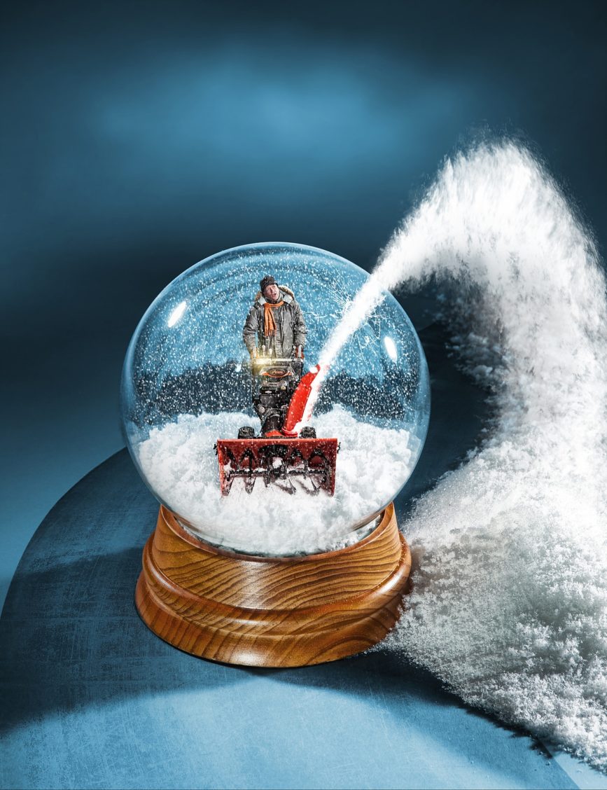 Photograph of a man snowblowing that has been photoshopped to appear in a snowglobe