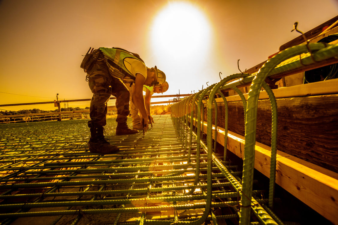 Industrial photograph of construction workers working with rebar on a hot sunny day