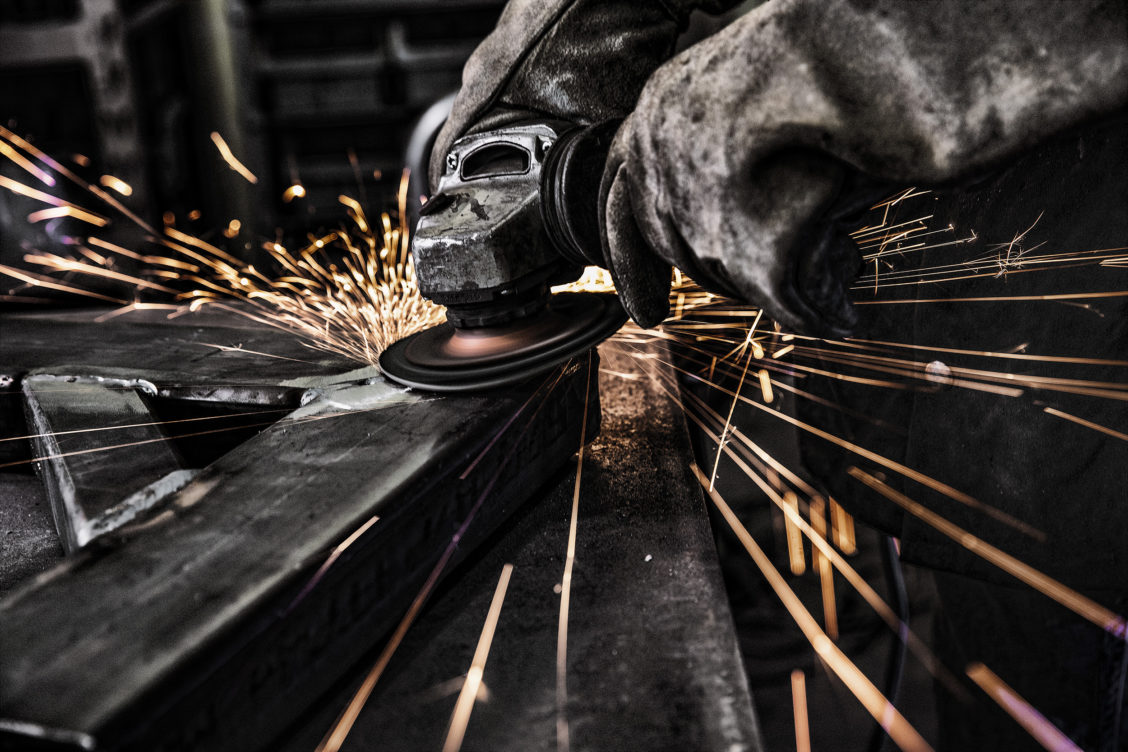 Photograph of sparks flying while hand holds welding equipment.