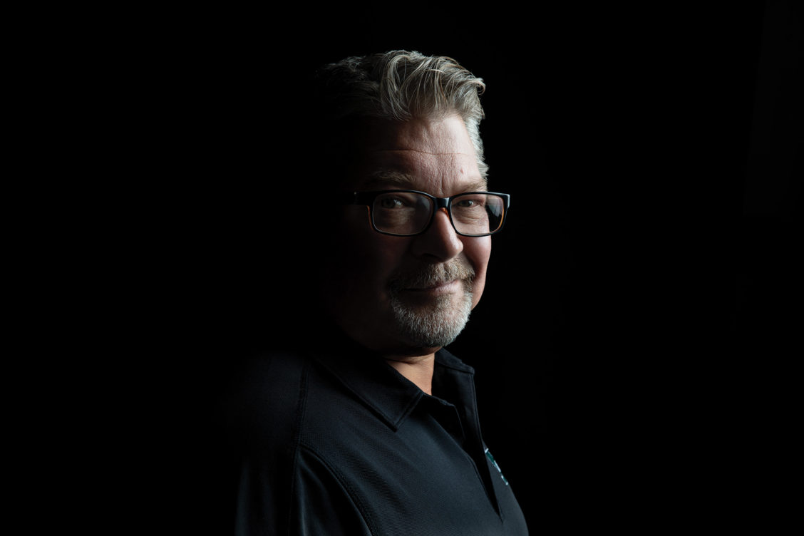 Headshot photography of a man in the shadows of a dark room