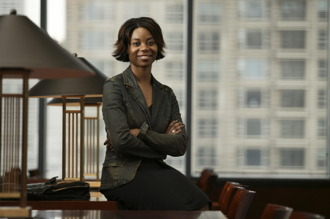 Corporate portrait of a woman casually sitting in an office setting.