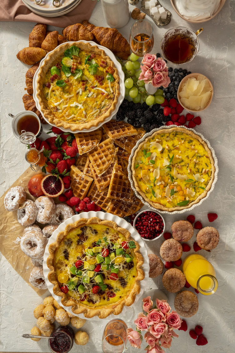 Food photography of a Mothers Day brunch spread with quiche, fruit, and baked goods