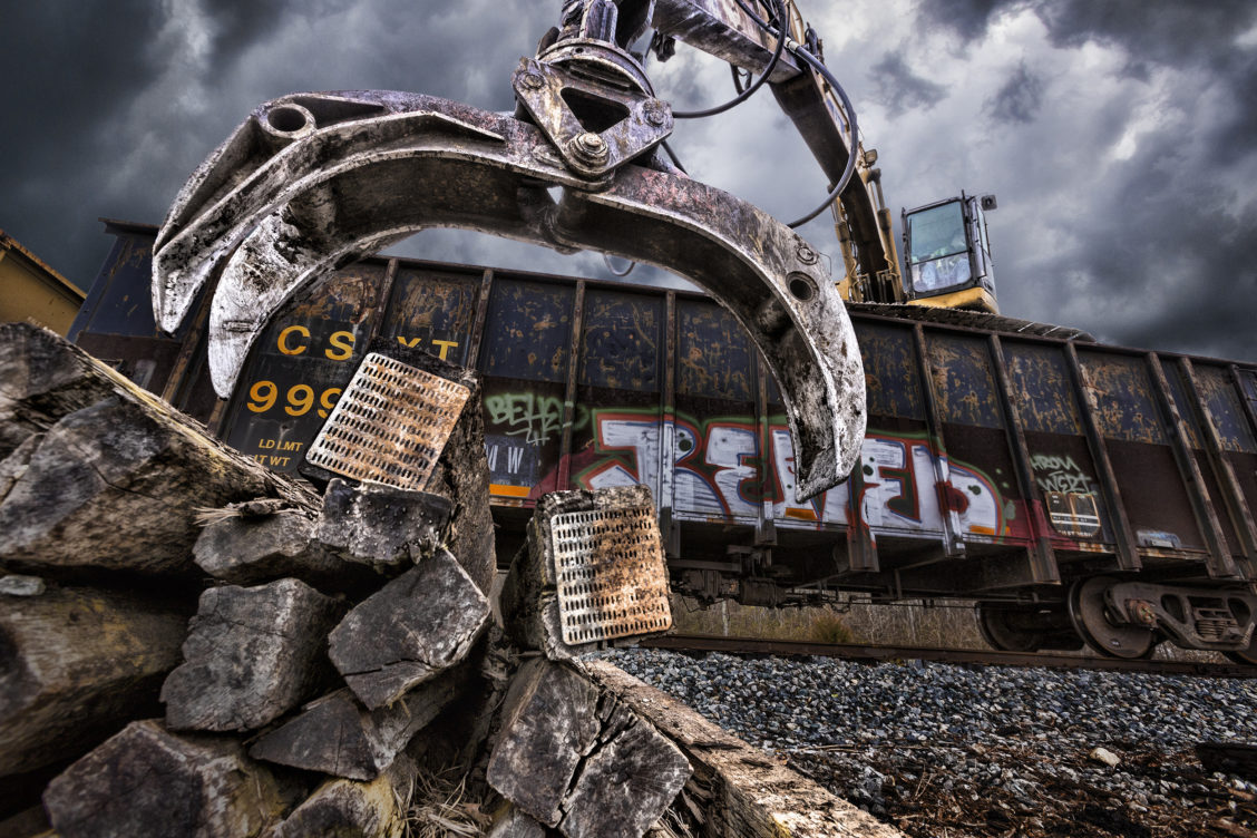 Photograph of machinery picking up heavy objects in an industrial setting.