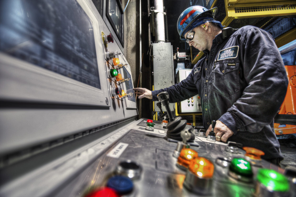 Photography of a control panel being operated on by an employee in an industrial setting.