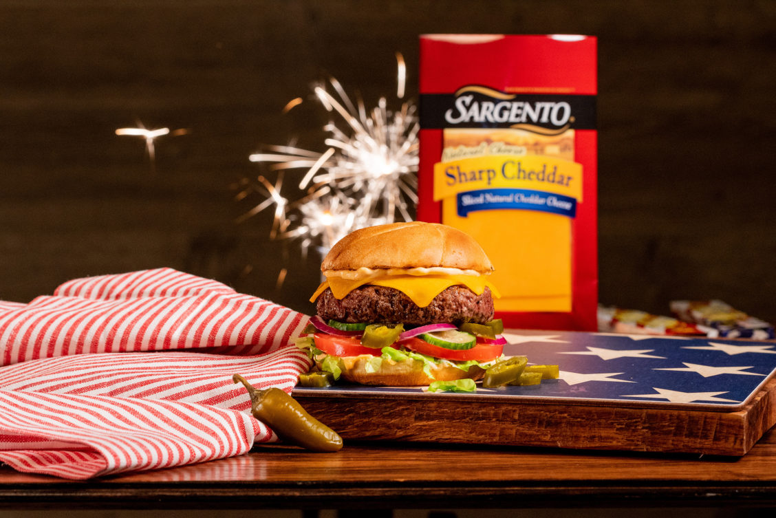 Patriotic food photography of Sargento cheese product on a burger with a firecracker.