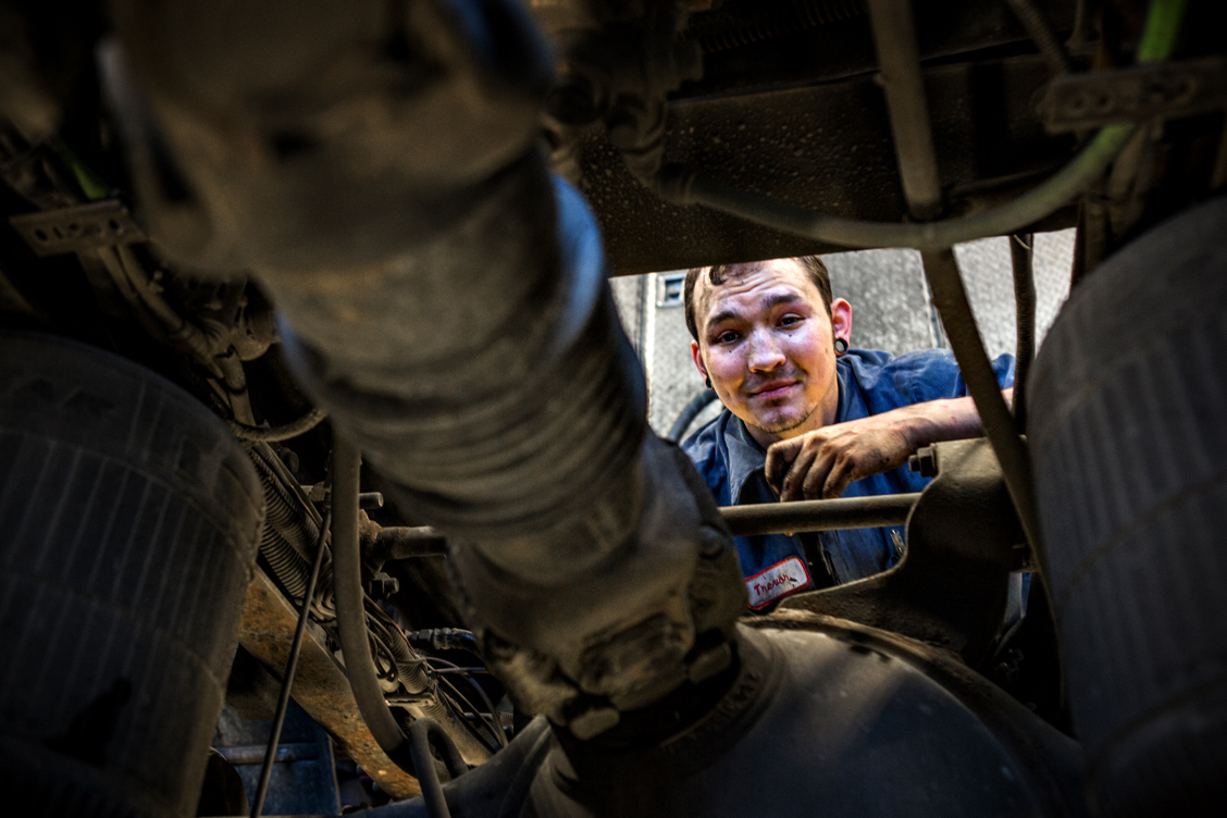Unique photography angle of a man looking under the hood of a vehicle
