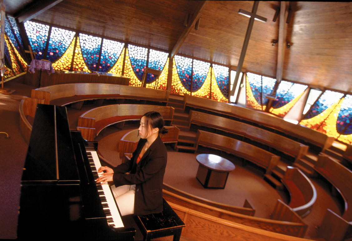 Photograph of a woman playing the piano in a mid century modern church