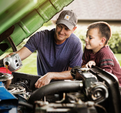 Lifestyle photography of a man and son changing oil in vehicle